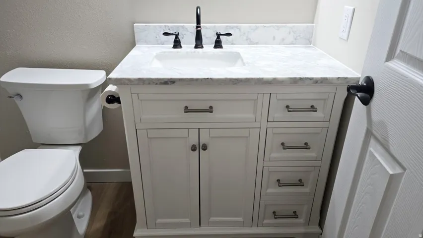 White vanity with a marble-finish countertop, integrated sink, and matte black faucet