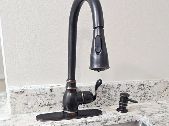 Stainless steel undermount sink with a garbage disposal and a gooseneck faucet in an oil-rubbed bronze finish