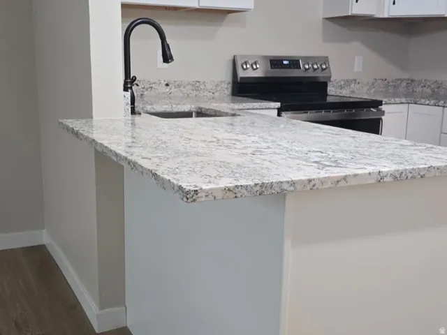 Kitchen island with light-toned granite countertop, featuring a black gooseneck faucet and undermount sink