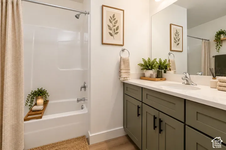 Bathroom featuring a tub/shower combination, single vanity with light-colored countertop, and olive-toned cabinetry