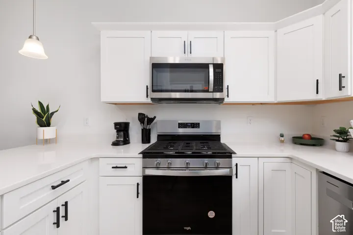 Kitchen featuring white shaker cabinetry with matte black hardware, stainless steel appliances, white countertops, and a built-in microwave