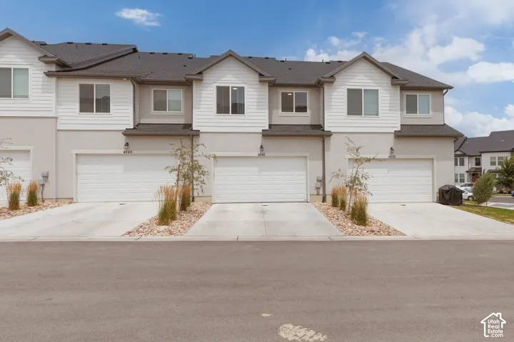 Contemporary townhome-style residences featuring light-toned siding and dark shingle roofs