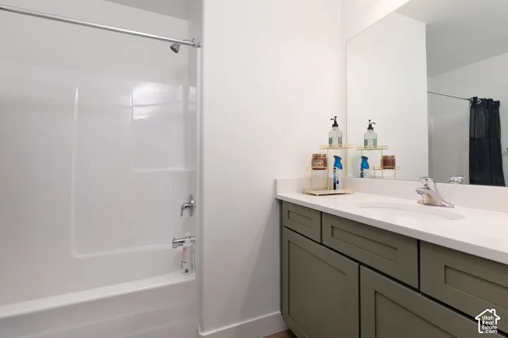 Bathroom featuring a single vanity with a light countertop, integrated sink, and an olive green cabinet