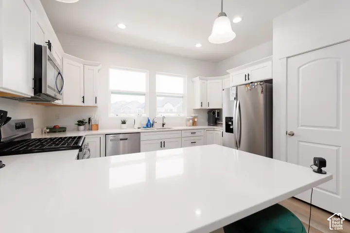 Spacious kitchen featuring an expansive island with a pristine white countertop, white cabinetry with dark hardware, stainless steel appliances, and a gas range
