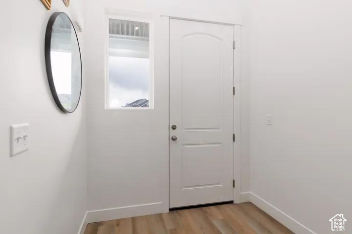 Entryway featuring a white paneled door, light wood-finish flooring, white baseboards, and a rectangular window
