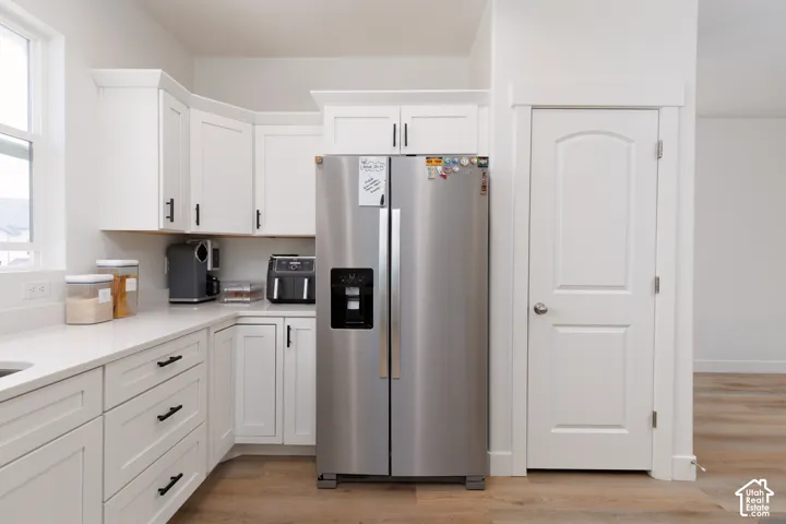 Kitchen featuring white shaker cabinetry with black hardware, white countertops, and wood-finish flooring