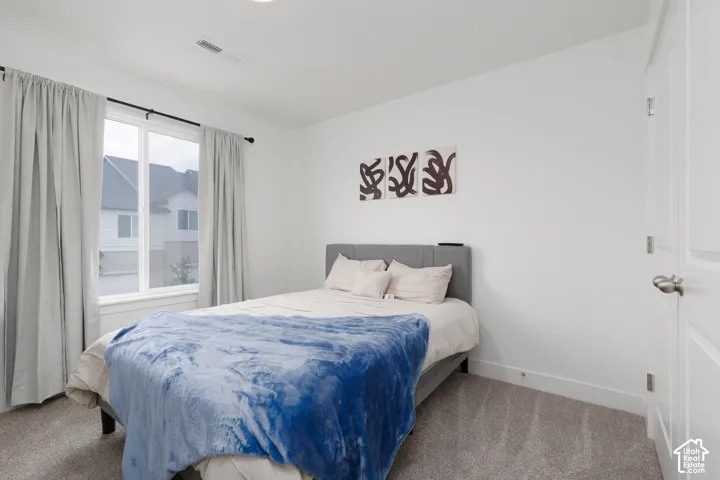 Carpeted interior space featuring white walls, a large window with white framing, and a recessed ceiling light