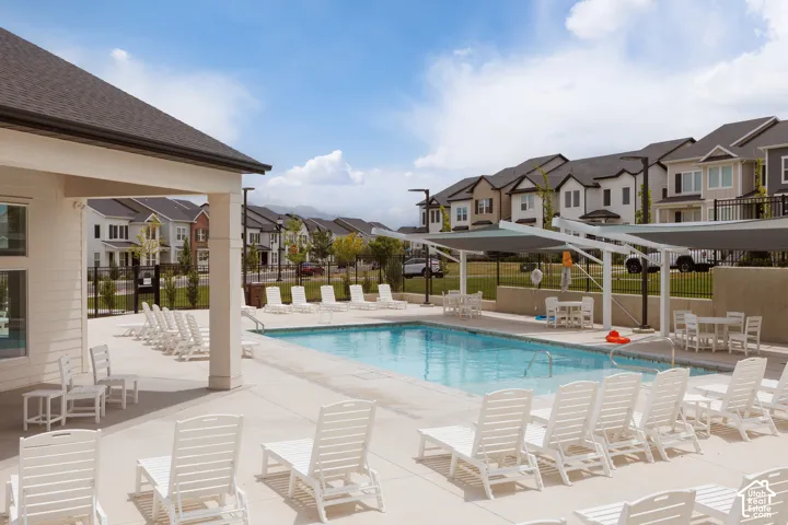 Expansive outdoor pool area featuring a concrete deck, multiple lounge chairs, and shaded dining areas