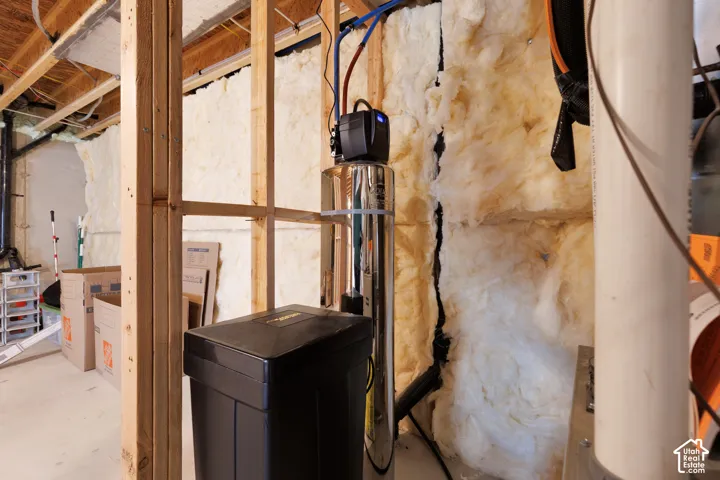 Utility area featuring a water filtration system, exposed wood framing, and wall insulation