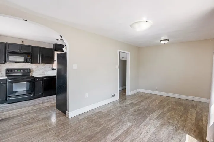 Open-concept living area featuring wood-finish flooring, neutral wall tones, and an arched entryway to the kitchen
