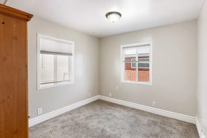 Bedroom featuring light gray wall paint, two windows with white blinds, gray carpeting, white baseboards, and a ceiling-mounted light fixture