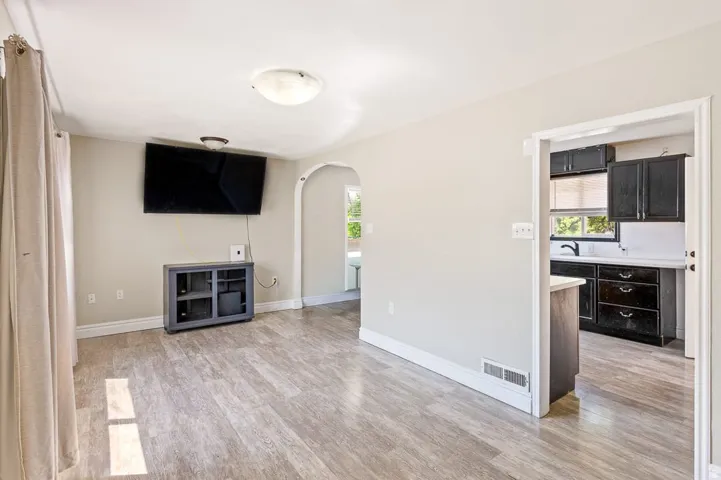 Open-concept living space featuring wood-finish flooring and light-toned walls