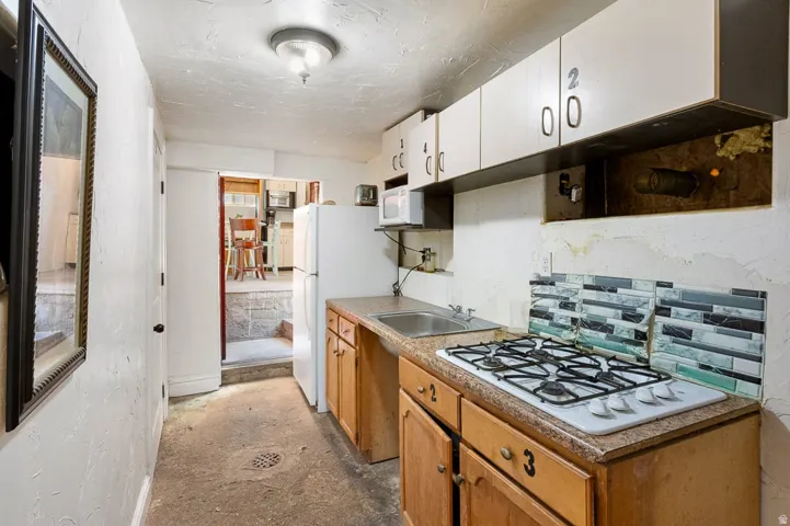Compact kitchen area featuring a gas cooktop, laminate countertops, and light wood cabinetry