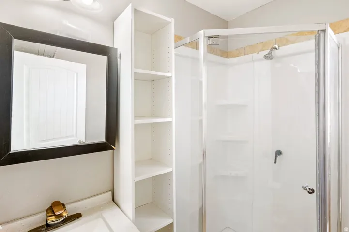Corner shower enclosure with glass panels, integrated shelving, and a showerhead