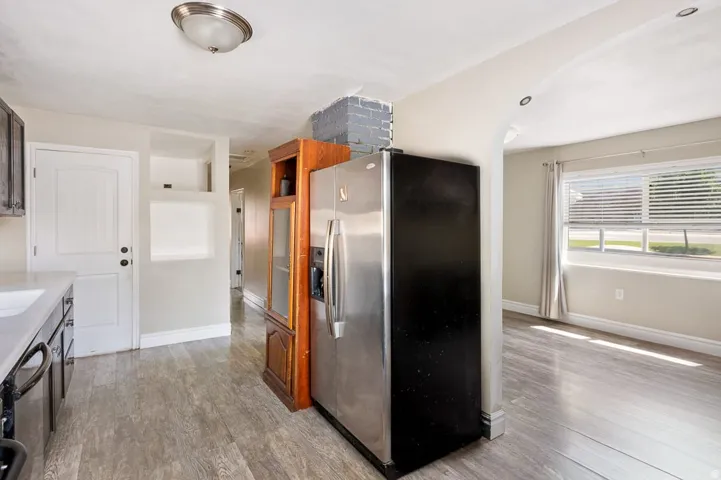 Kitchen area with wood-finish flooring, white countertops, and dark cabinetry