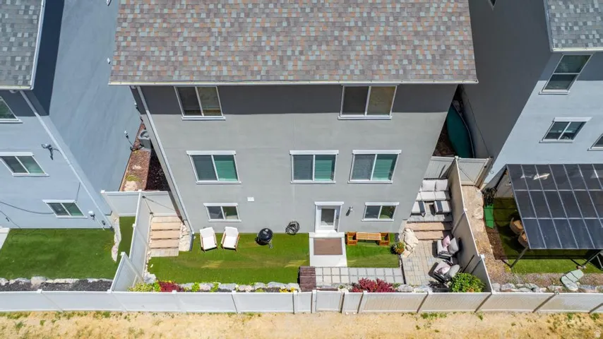 Rear exterior featuring a manicured lawn, a paver patio area, and a white privacy fence