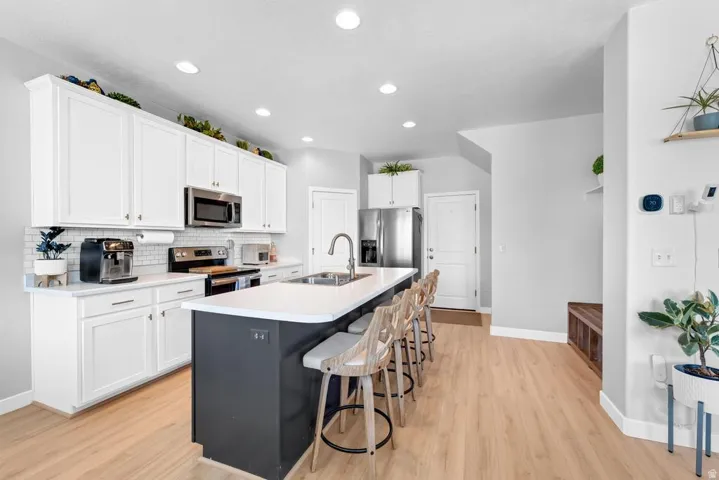 Modern kitchen featuring white cabinetry, light-toned wood-finish flooring, and recessed lighting