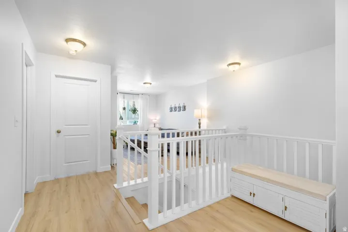 Hardwood-finish flooring throughout, featuring a white painted staircase railing and a built-in storage bench