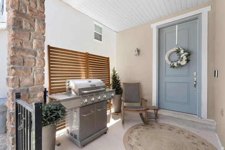 Covered porch featuring a stone column, wood slat privacy screen, and a paneled front door
