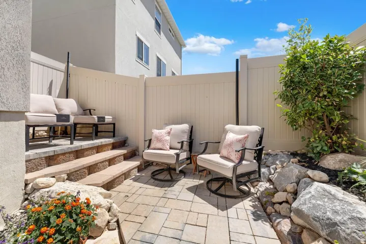 Private patio featuring paver stone flooring, a multi-level retaining wall, and a full privacy fence