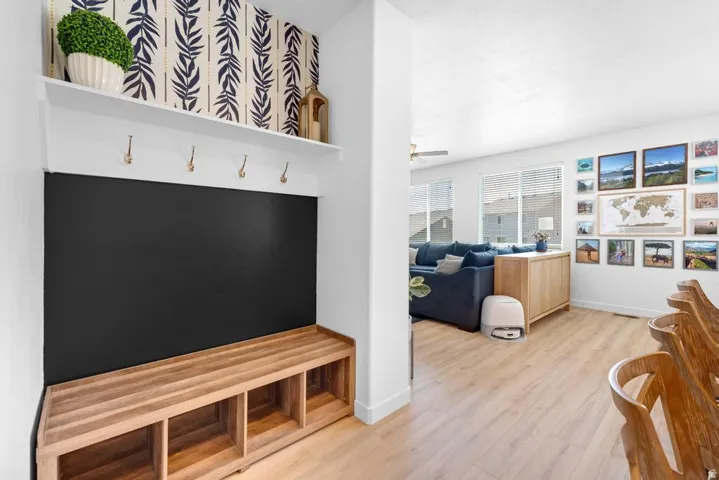 Entryway mudroom featuring a built-in bench with cubby storage, wall-mounted hooks, and an upper display shelf