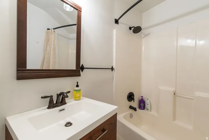 Bathroom featuring a white integrated sink vanity with a wood-finish cabinet, dark bronze hardware, and a framed mirror