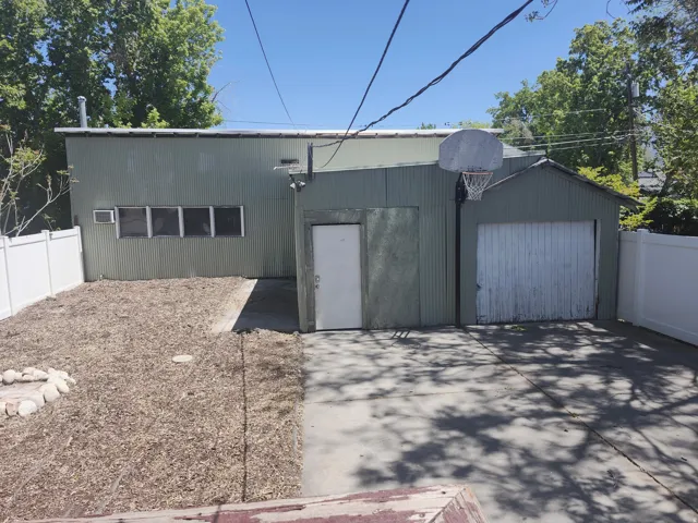 Detached corrugated metal structure featuring multiple windows, a garage door, and a separate entry door