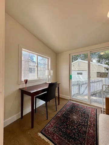 Room featuring wood-finish flooring, a vaulted ceiling, and white baseboards