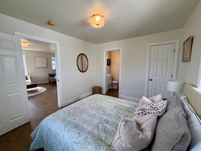 Interior room featuring neutral wall tones, wood-finish flooring, a paneled door, and an overhead light fixture