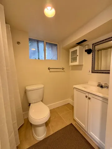 Bathroom featuring a white vanity with built-in sink, framed mirror, and tiled flooring