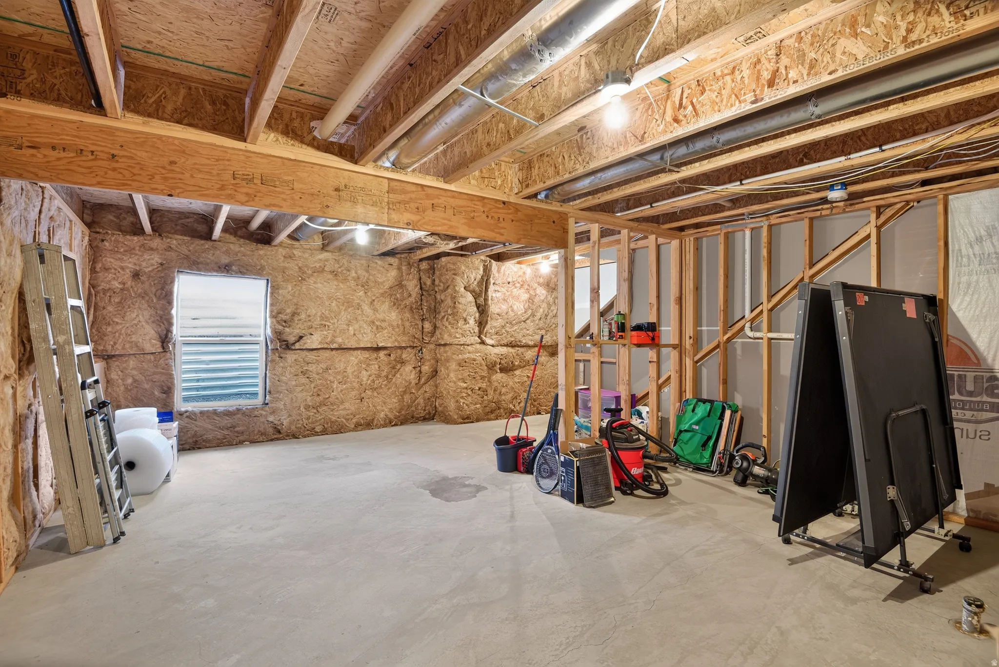 Unfinished basement space with exposed wood framing and concrete flooring