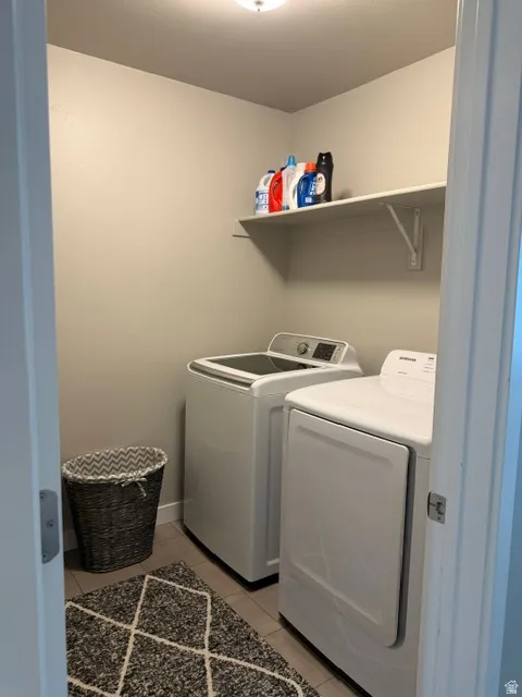 Dedicated laundry area featuring a wall-mounted shelf, neutral wall tones, and tile flooring
