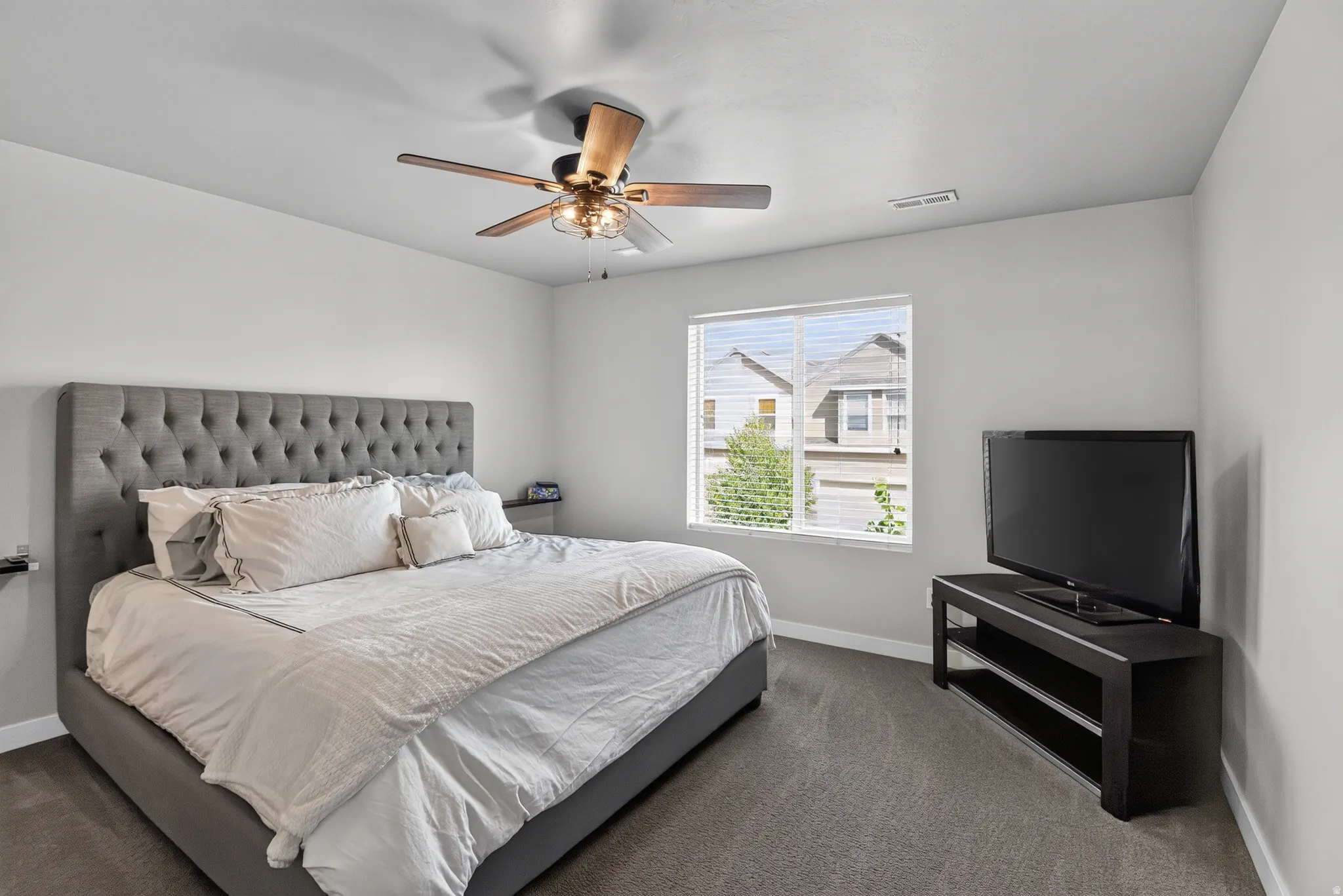Carpeted bedroom with a single window featuring horizontal blinds