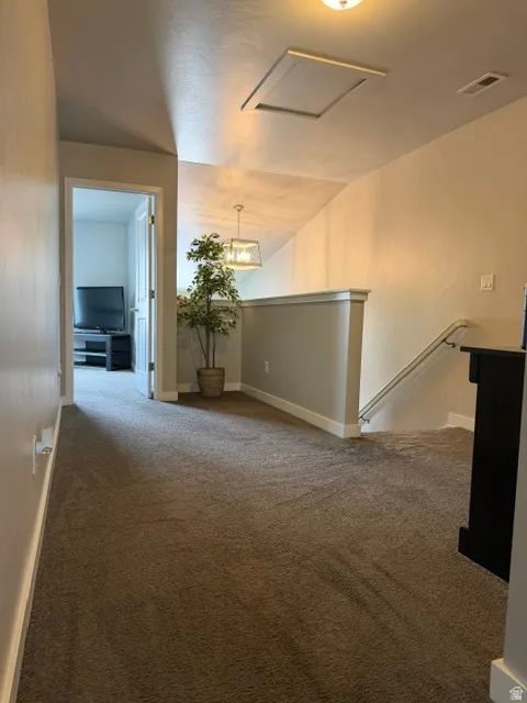 Carpeted hallway with a sloped ceiling and a white railing