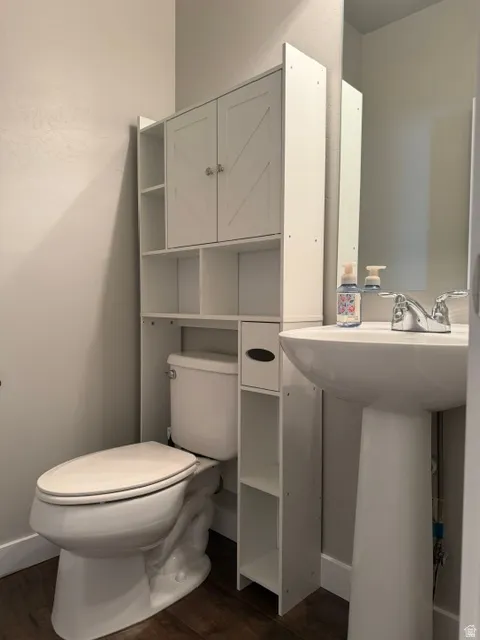 White pedestal sink with chrome faucet, complemented by dark wood-finish flooring