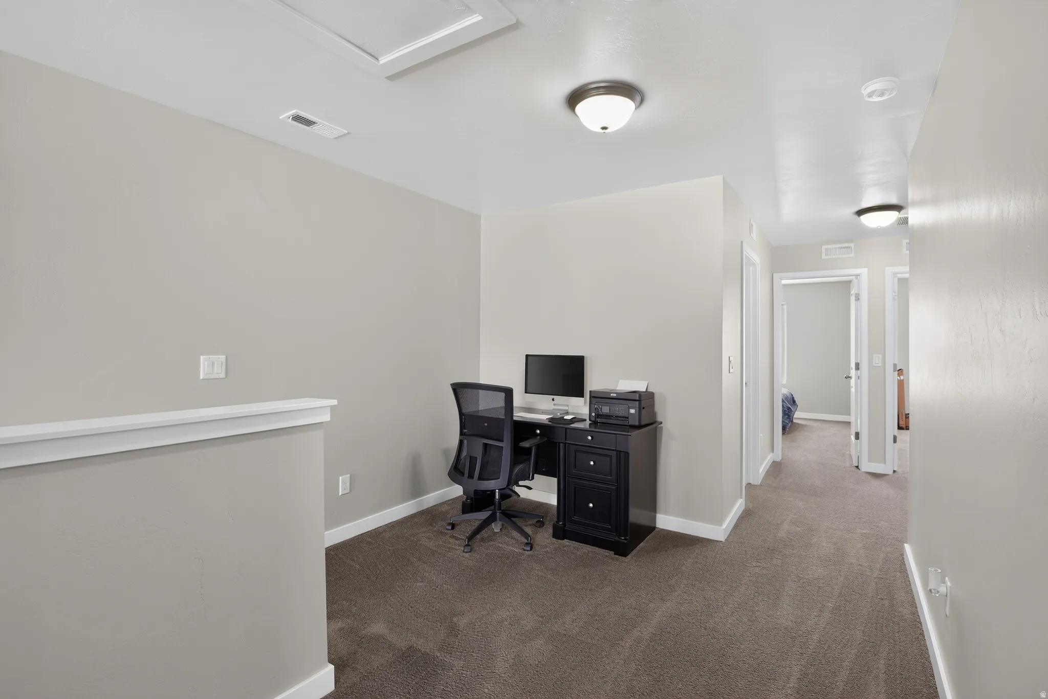 Carpeted loft area with light gray wall paint, white trim, and flush-mount ceiling lighting