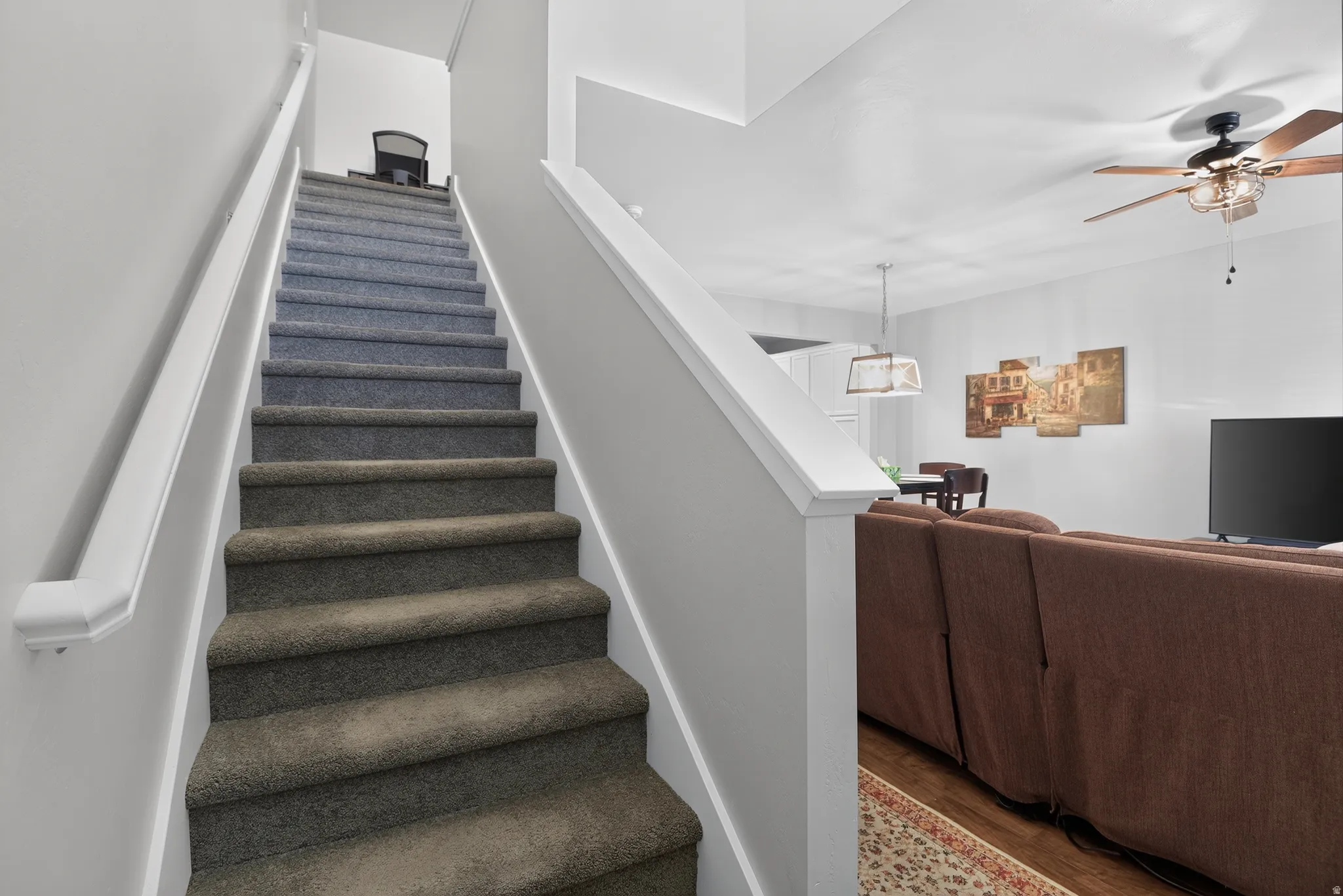 Carpeted staircase with white handrails and painted risers