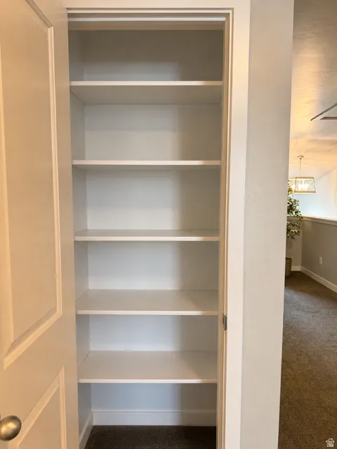 Built-in shelving unit with multiple white shelves, a white door, and a brushed nickel doorknob