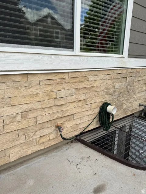 Stacked stone veneer siding with a white window trim and gray horizontal siding