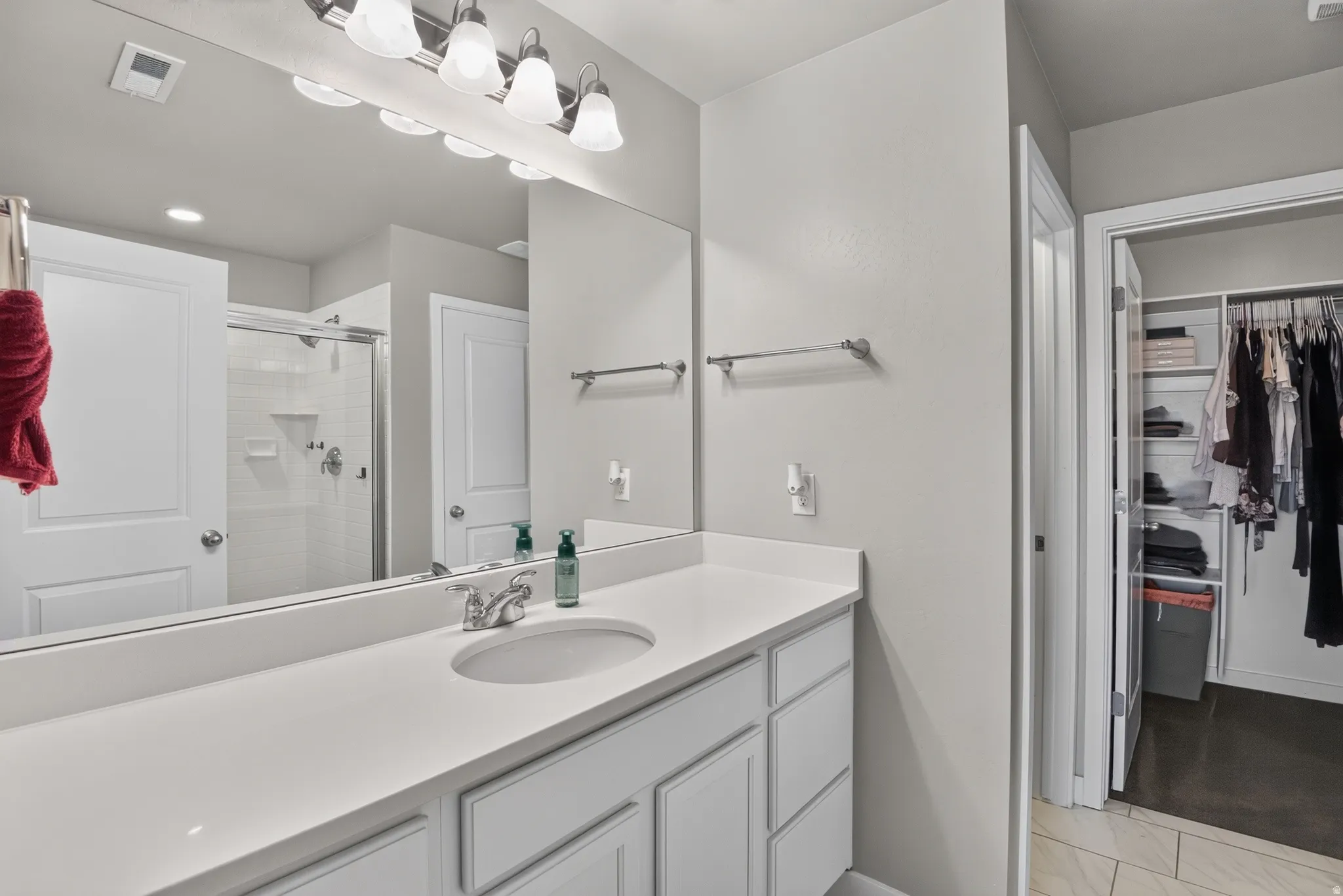 Bathroom featuring an expansive vanity with an undermount sink and a large wall-mounted mirror