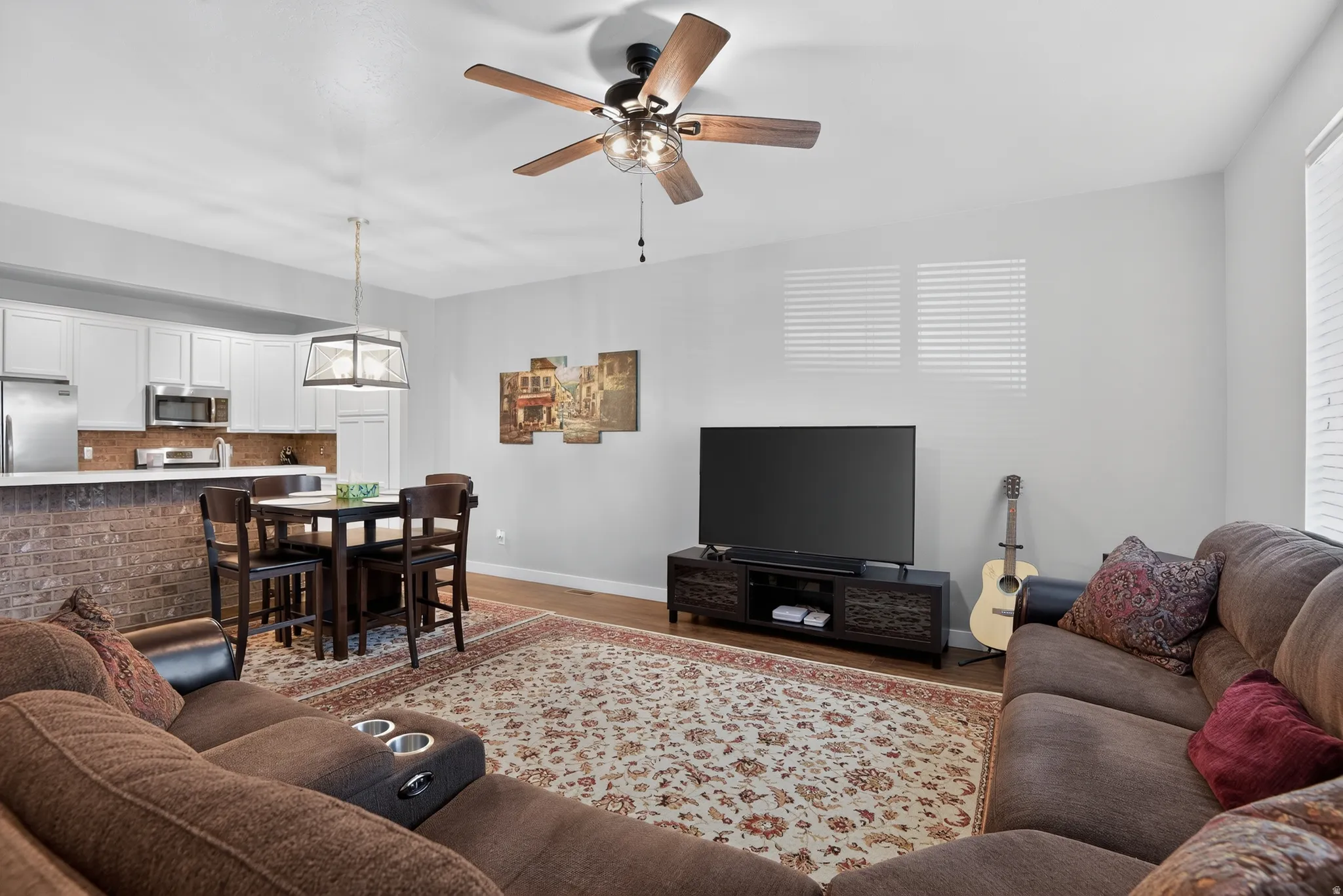 Open-concept living area featuring wood-finish flooring and a ceiling fan