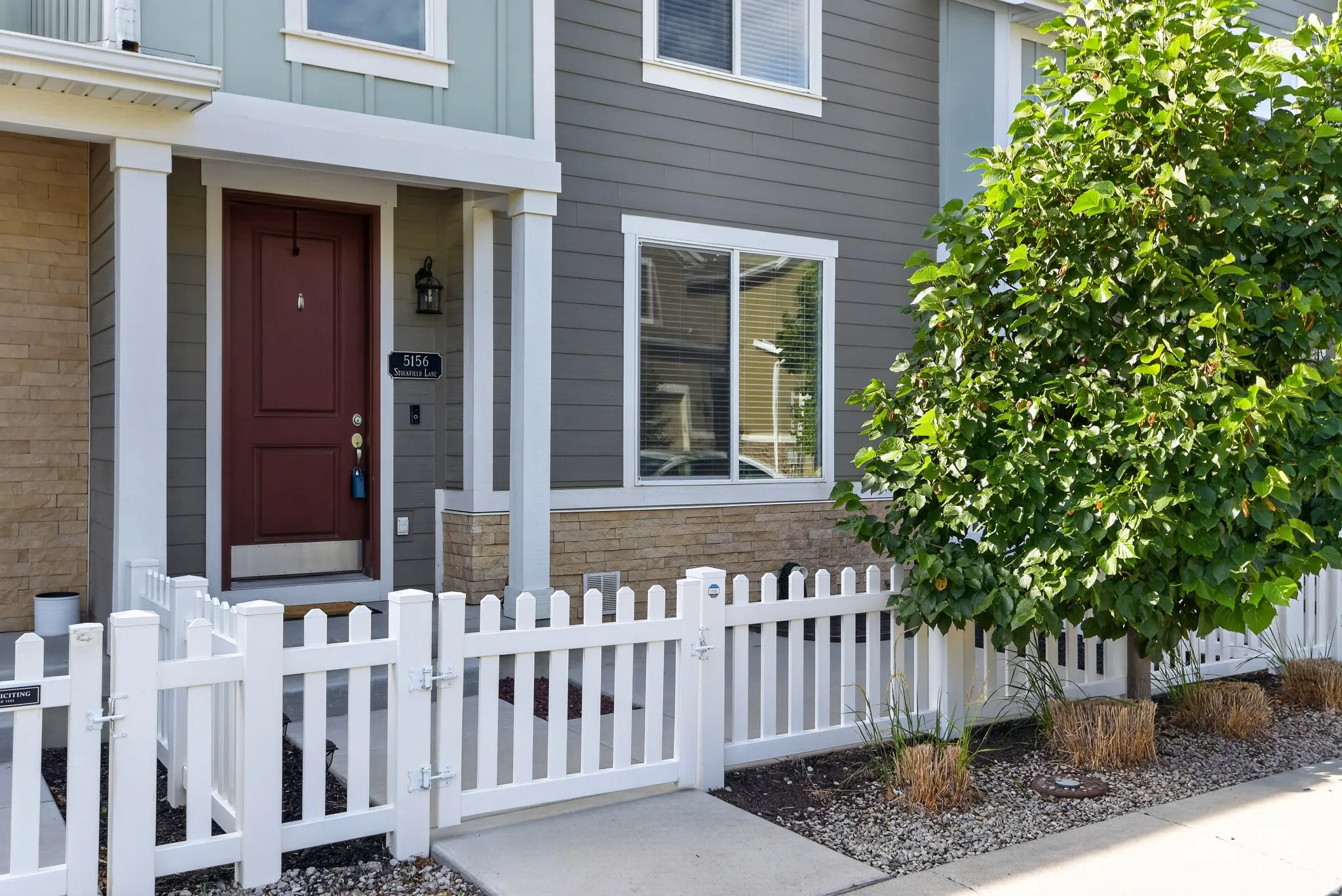 Two-story townhome with a rich burgundy entry door, white trim, and a decorative outdoor sconce