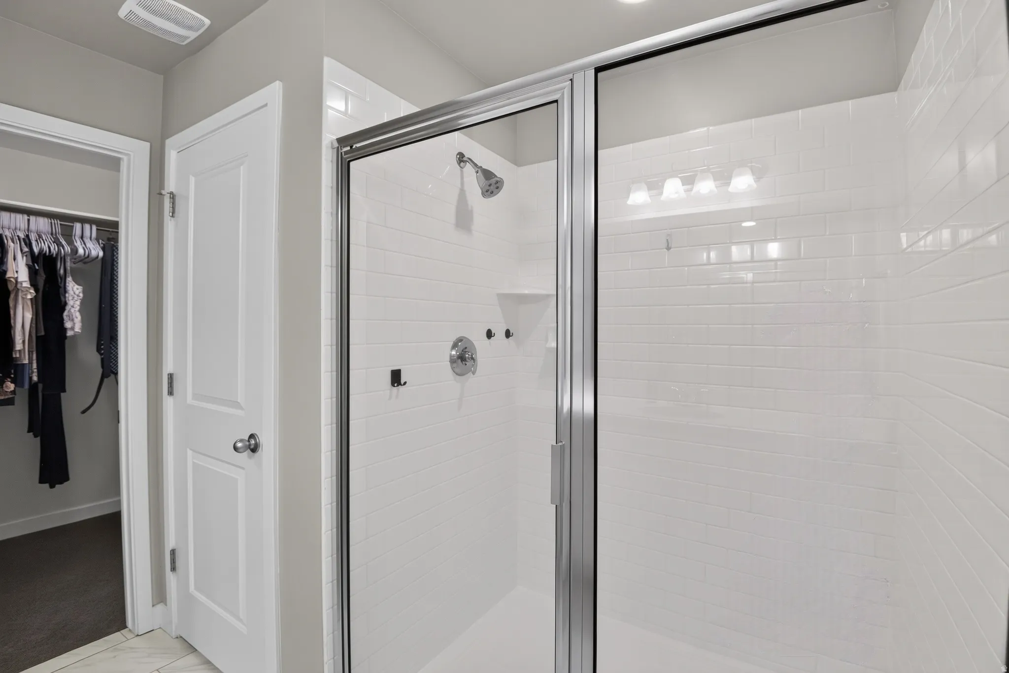 Walk-in shower with clear glass enclosure, subway tile walls, built-in shelving, and polished chrome fixtures