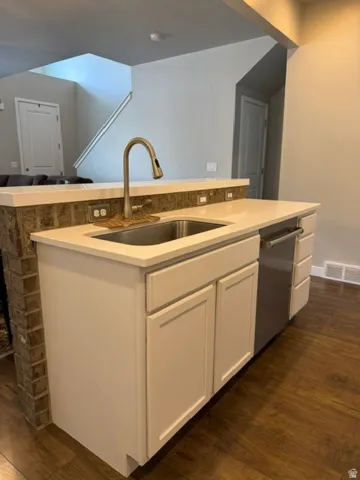 Kitchen island featuring a stainless steel sink, a pull-down faucet, and a built-in dishwasher