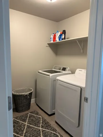 Dedicated laundry area featuring a wall-mounted shelf, neutral wall tones, and tile flooring