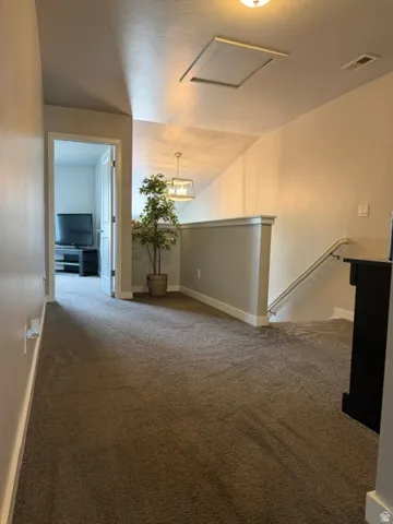 Carpeted hallway with a sloped ceiling and a white railing