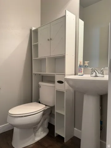 White pedestal sink with chrome faucet, complemented by dark wood-finish flooring