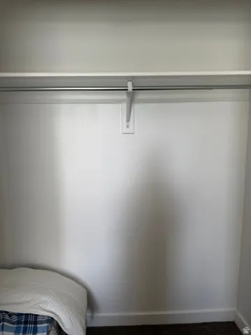 White shelving unit and metal hanging rod within a closet space