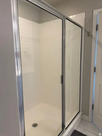 Walk-in shower featuring subway tile walls, a white shower pan, and clear glass sliding doors with metal framing