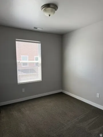 Room featuring neutral wall paint, dark patterned carpeting, and white baseboards
